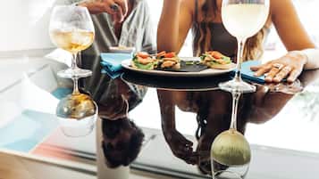 A dining table with a plate of food and two wine glasses.