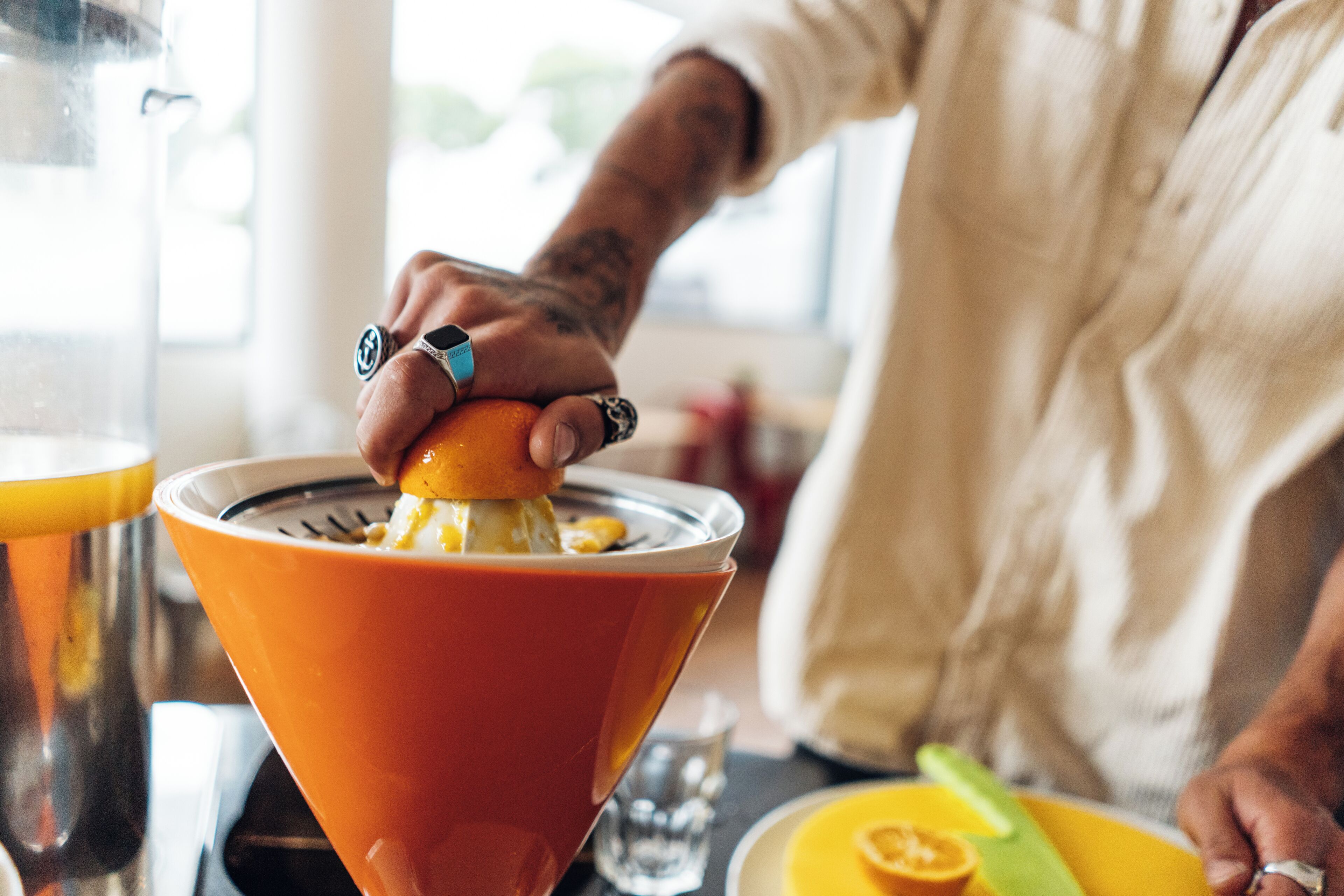 A person squeezing an orange into a bowl.