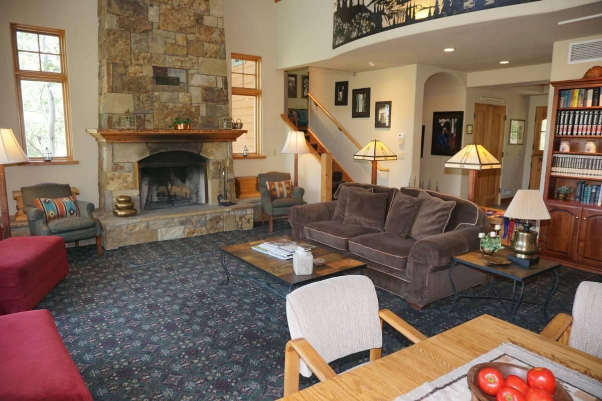 A cozy living room with a stone fireplace, a comfortable sofa, a wooden coffee table, and a bookshelf.