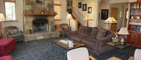 A cozy living room with a stone fireplace, a comfortable sofa, a wooden coffee table, and a bookshelf.