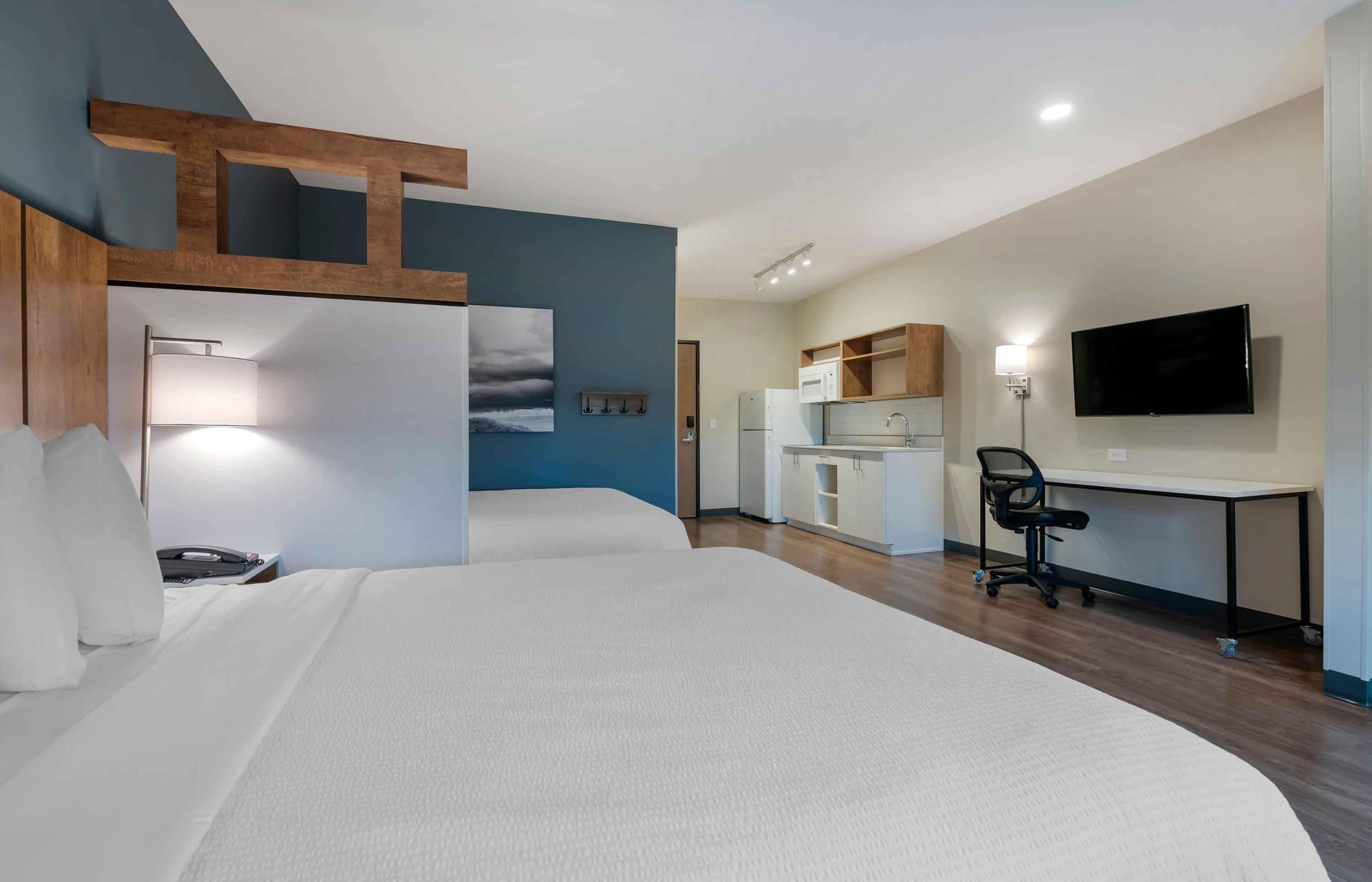 Een hotelkamer met een bed, bureau, kitchenette en televisie.