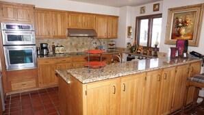 A kitchen with wooden cabinets, a granite countertop, and a double oven. - 35 Alpine Ln (Snowmass Village)