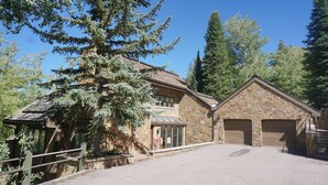 A stone building with a garage, a covered walkway, and a large tree in front. - 35 Alpine Ln (Snowmass Village)