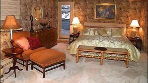 A bedroom with a large bed, a wooden bench, a dresser, two lamps, and a mirror. - 35 Alpine Ln (Snowmass Village)