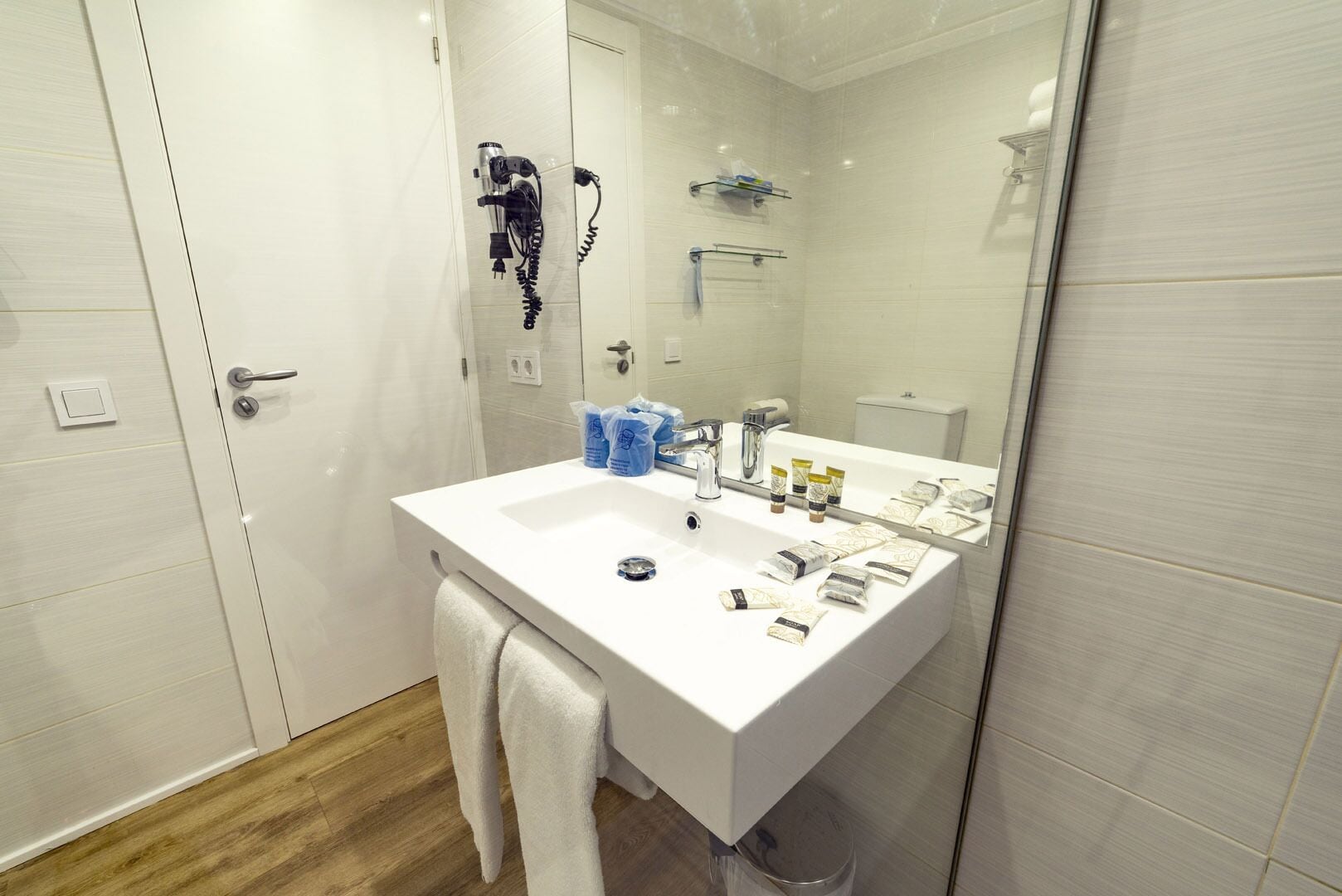 Uma casa de banho moderna com lavatório branco, espelho e porta-toalhas.