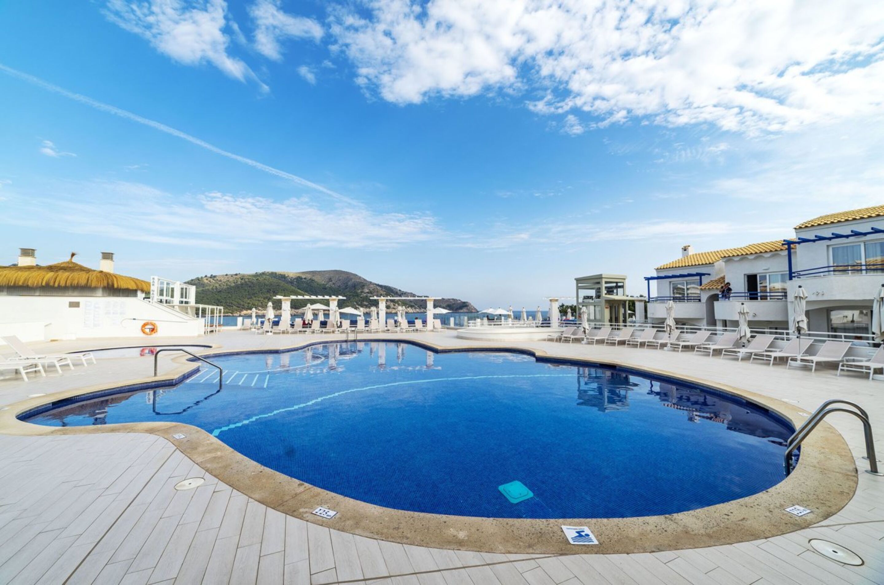 Una piscina con sillas de descanso y un puesto de socorristas.