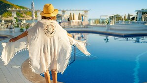En person promenerar längs poolkanten med utsikt över ett semesterområde.