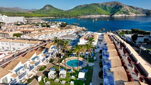 Ett hotell vid kusten med pool, utsikt över stranden och flera balkonger.