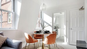 A modern dining area with a round table, four chairs, and a chandelier. - The Wellington Suite next to Sloane Square (London)
