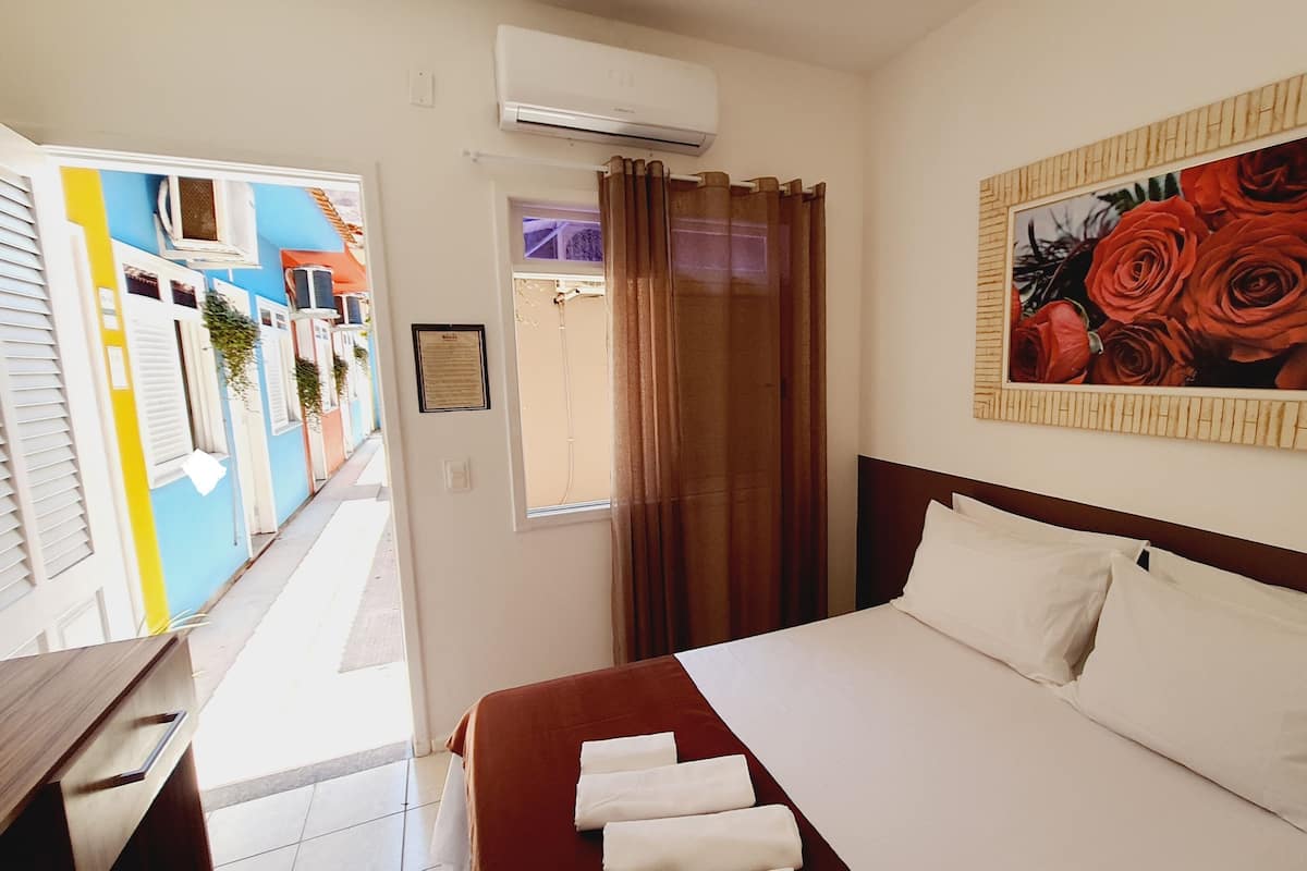 Ein Hotelzimmer mit einem Bett, einer Rosenblume-Abbildung und Blick auf farbenfrohe Gebäude.