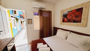 Ein Hotelzimmer mit einem Bett, einer Rosenblume-Abbildung und Blick auf farbenfrohe Gebäude.