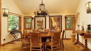 A dining area with a wooden table and chairs, a chandelier, and framed artwork on the walls.