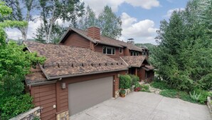 A two-story house with a brown exterior, a garage, and a stone wall.