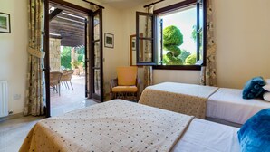 A hotel room with two beds, a chair, and a view of the garden through a window. - Villa 64 Anarita - Three Bedroom Villa, Sleeps 6 (Kouklia)