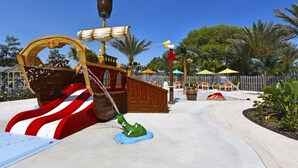 A pirate-themed play area with a ship-shaped slide, a green crocodile ride, and a wooden fence.