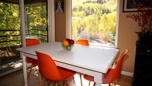 Una mesa de comedor con cuatro sillas naranjas y un frutero.