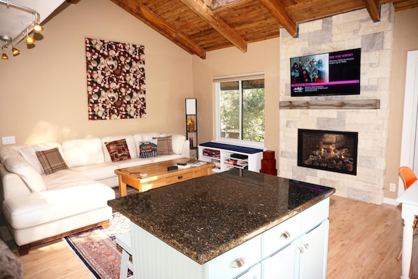 A living room with a stone fireplace, a large TV mounted on the wall, and a cozy seating area with a sofa and coffee table.