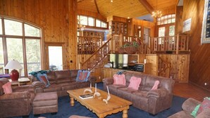 Ein geräumiges Wohnzimmer mit einer großen Holztreppe, Ledersofas und einem Couchtisch in der Mitte.