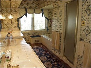 Ein Badezimmer mit einem großen Waschbecken, einer Badewanne, einem Fenster mit Vorhängen und einer Duschkabine.