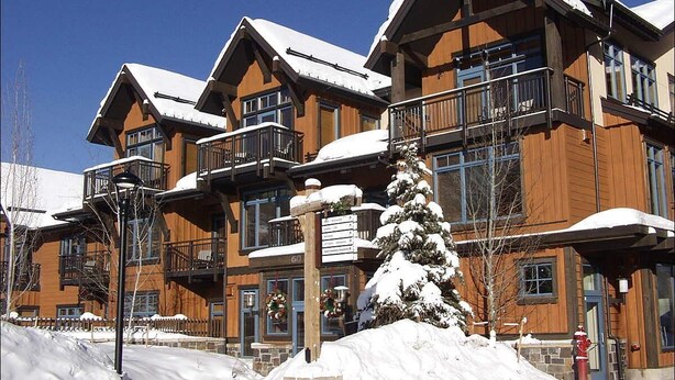 A multi-story wooden building with balconies and a snow-covered roof.