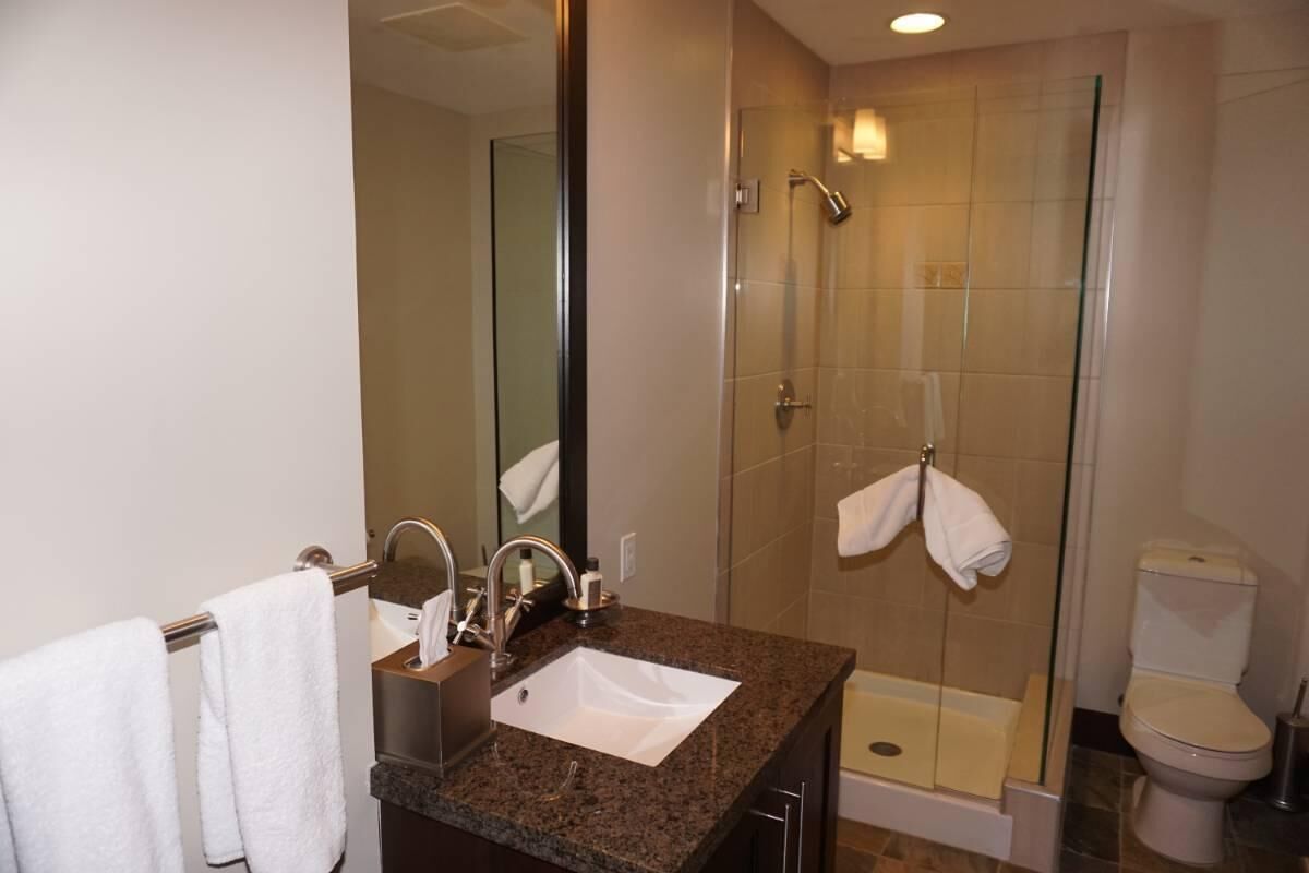 Un baño moderno con lavamanos de granito, ducha con cerramiento de vidrio y un inodoro.