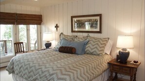 A bedroom with a large bed, two bedside tables, a chair, and a window with blinds. - 1131 Faraway Rd (Snowmass Village)