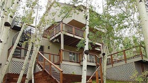 A multi-level wooden cabin with a balcony and stairs, surrounded by birch trees. - 1131 Faraway Rd (Snowmass Village)
