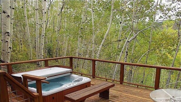 A wooden deck with a hot tub, a bench, and a table. - 1131 Faraway Rd (Snowmass Village)