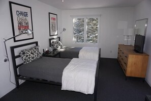 A bedroom with two beds, a dresser, a TV, and framed motivational posters.
