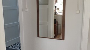 Ein Flur mit einem großen Spiegel an der Wand, einer blauen Tür und einem gemusterten Teppich.
