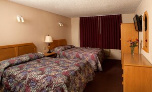 A hotel room with two beds, a nightstand, a lamp, a mirror, a dresser, and a window with curtains.