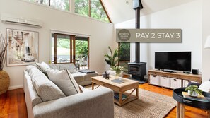 A modern living room with a sofa, coffee table, TV, and a fireplace. - Collins Street House in Red Hill (Red Hill)