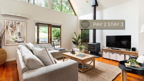 Ein modernes Wohnzimmer mit Sofa, Couchtisch, Fernseher und Kamin.