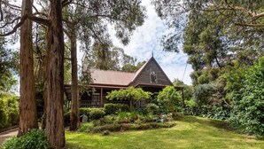 Une maison entourée d’une végétation luxuriante et d’arbres.