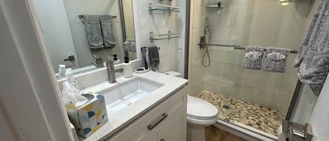 Een moderne badkamer met een groot wastafel, toilet en douchecabine met glazen wanden.