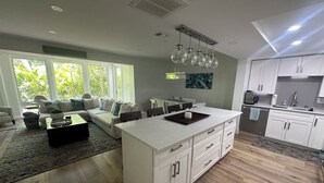 Una cucina moderna con mobili bianchi, un'isola centrale e una zona pranzo con divano e tavolino.