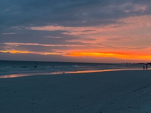 Une plage au coucher du soleil, avec des vagues et une jetée.