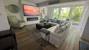 Un soggiorno moderno con una grande TV a schermo piatto, un camino, un divano e una zona pranzo.