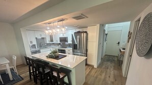 Una cucina moderna con isola centrale, elettrodomestici in acciaio inossidabile e un lampadario a sospensione.