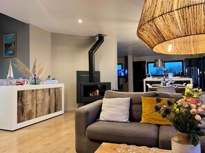 A modern living room with a sofa, a coffee table, a fireplace, and a kitchen area in the background.