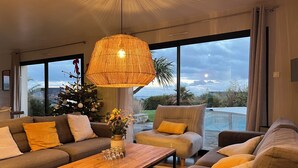 Un salon moderne avec une grande fenêtre, un sapin de Noël et une table basse en bois.
