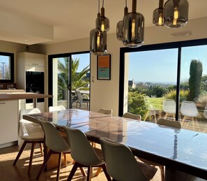 Een moderne keuken met een grote eettafel en stoelen, een inbouwoven en uitzicht op het buitengebied.