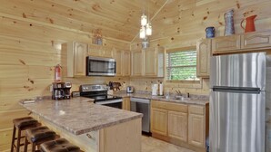 Una cocina con armarios de madera, un refrigerador de acero inoxidable, un microondas y una cafetera.
