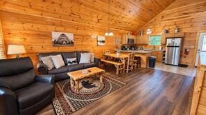 A cabin interior with a living room, dining area, and kitchen.
