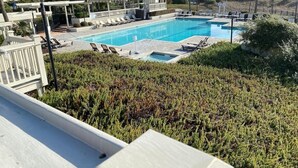 A swimming pool with lounge chairs, a small pavilion, and a view of tall buildings in the background.