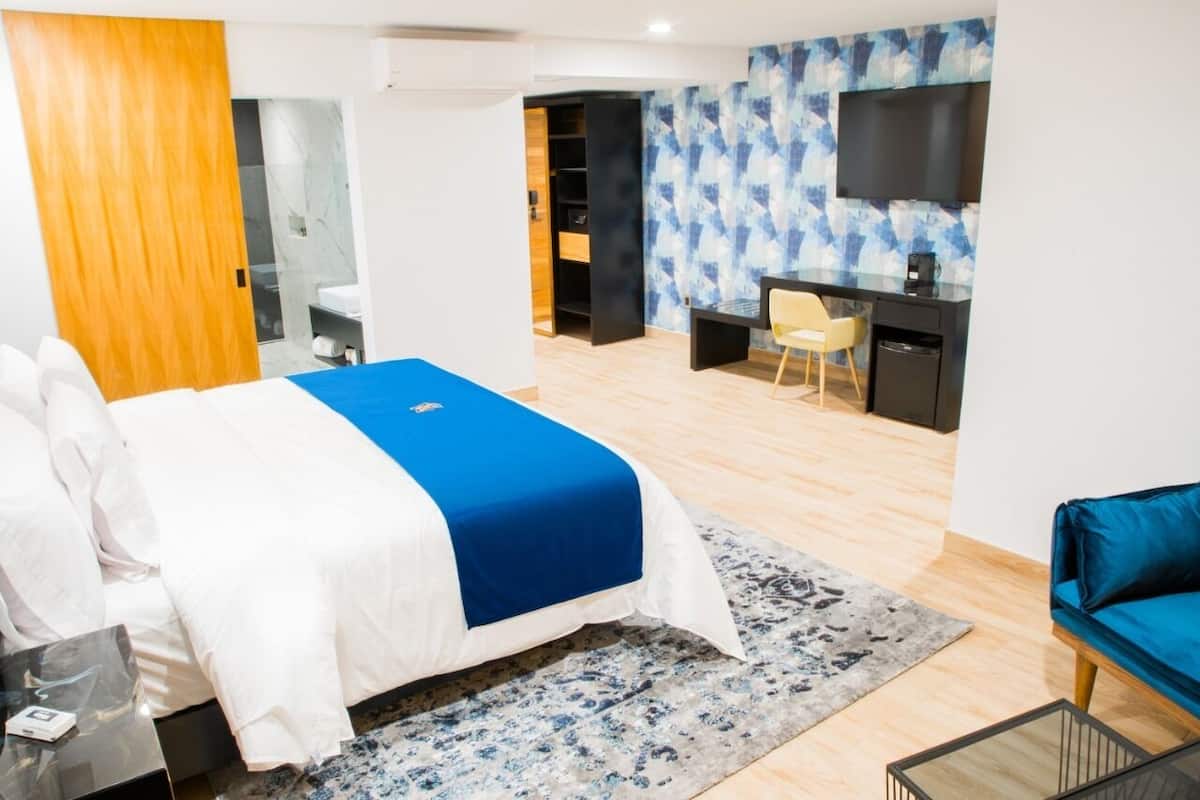 A modern hotel room with a bed, a desk, a TV, and a bathroom.