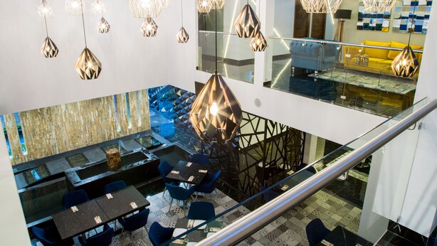 Un interior moderno con comedor, varias lámparas colgantes y una escalera.