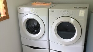 Deux machines à laver à chargement frontal, superposées, sont installées dans un coin, sur un sol carrelé.