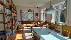 A cozy room with a long table, chairs, a sofa, and a bookshelf filled with books. - dasokerhaus.com (Altenau)