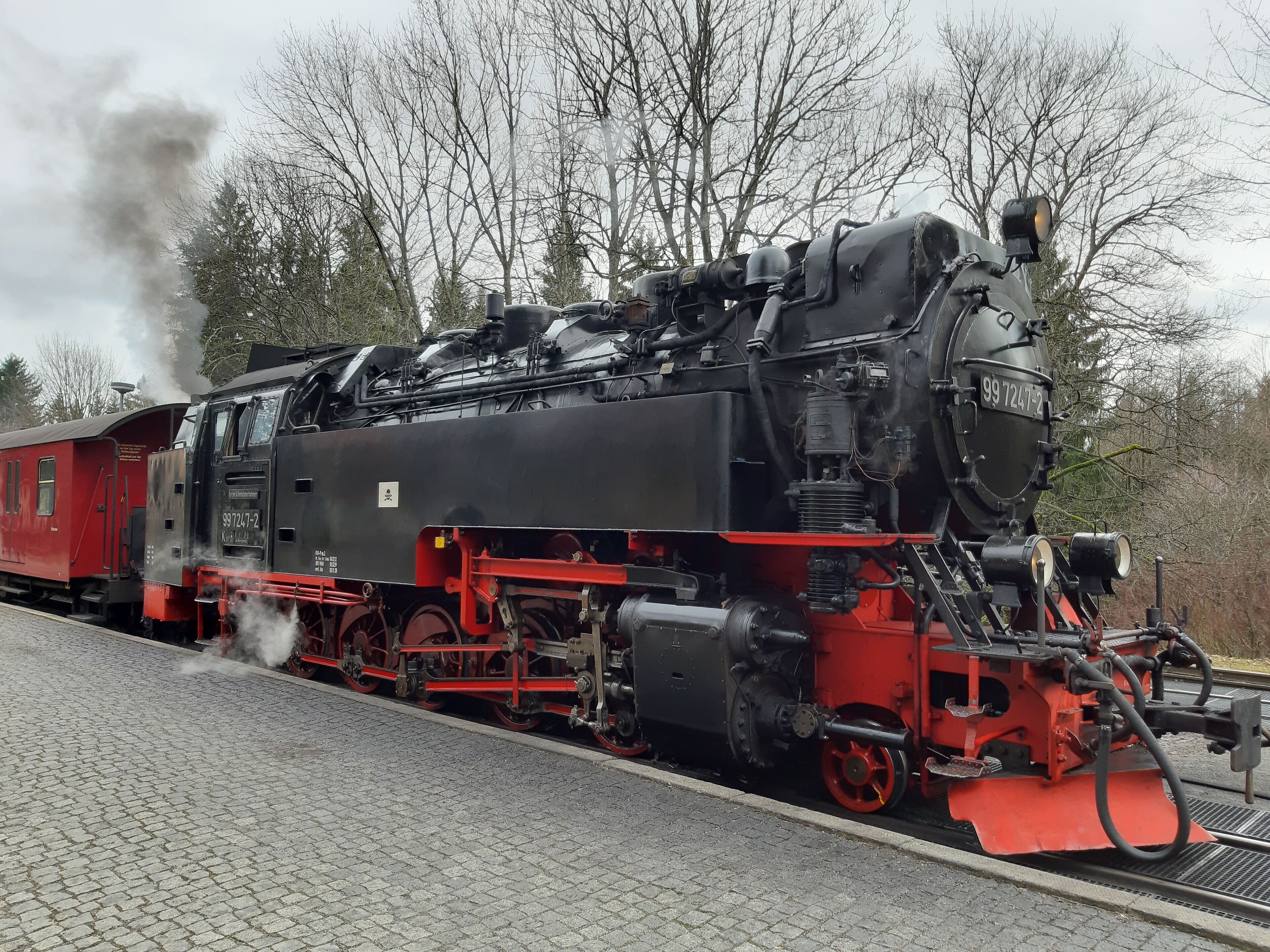 A steam locomotive with a red and black color scheme, number 99 7247-2, on a railway track.